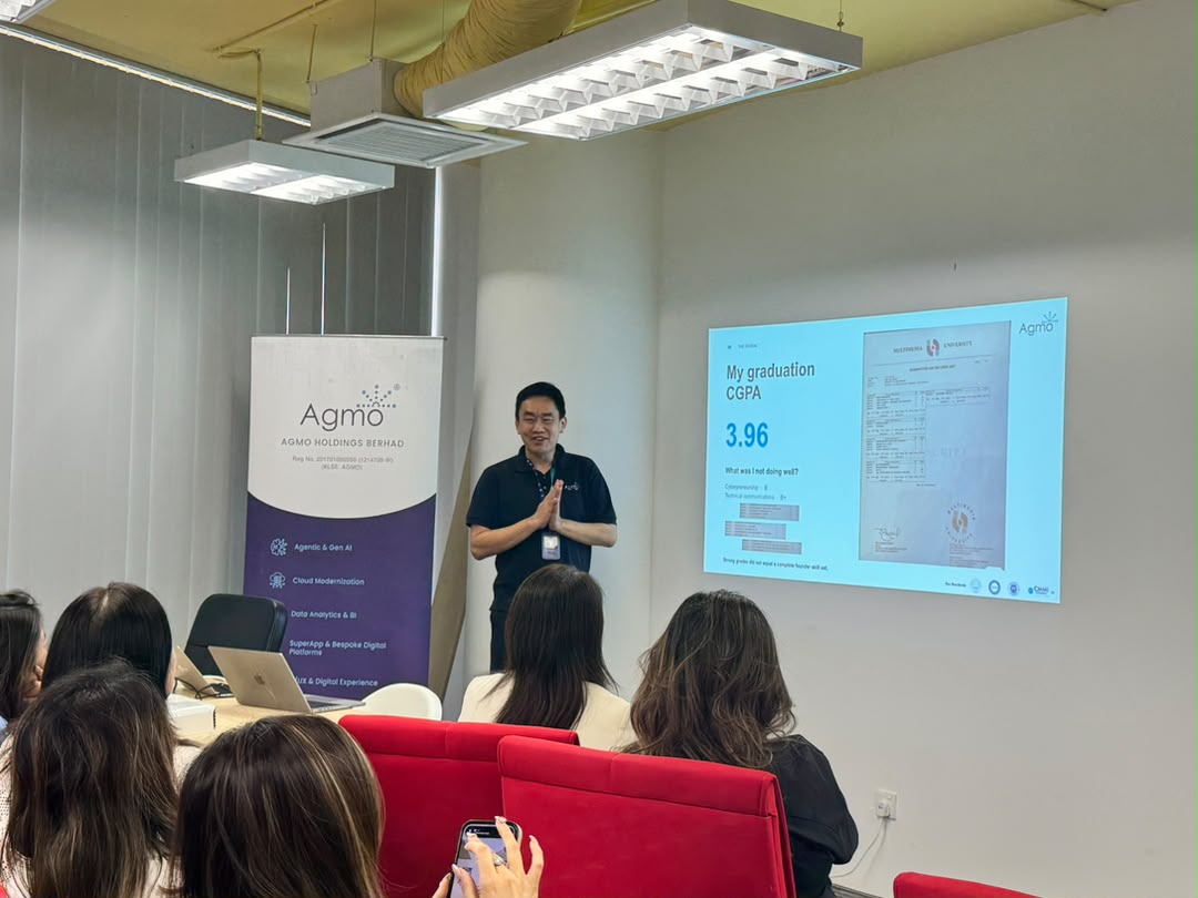 An Agmo speaker presenting to the visiting delegation, beside an Agmo roll-up banner