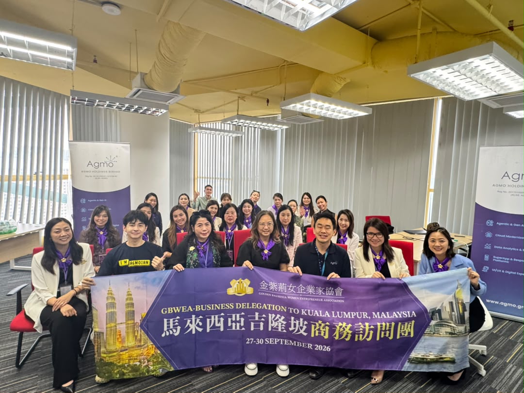 Members of the GBWEA business delegation from Hong Kong holding their banner in an Agmo meeting room, with Agmo roll-up banners behind them
